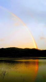 Scenic view of rainbow over lake against sky