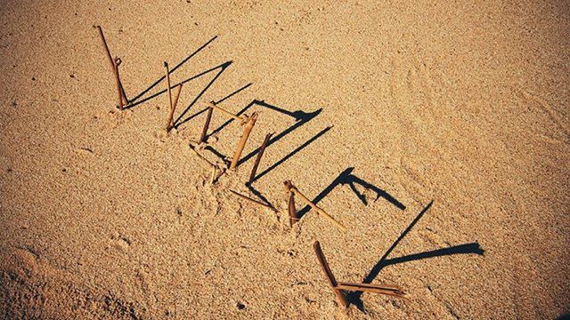 text, sand, western script, communication, beach, high angle view, capital letter, footprint, no people, outdoors, ideas, day, close-up, sunlight, shore, textured, creativity, shadow, identity, art and craft