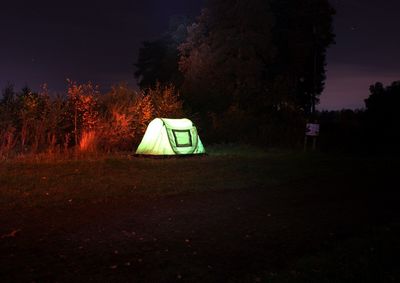 Illuminated tent on field against sky at night
