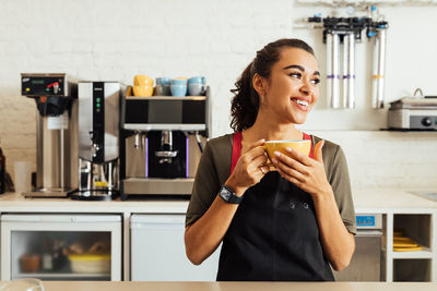 Portrait of smiling woman holding coffee at home