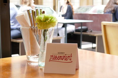 Reserved sign by flower in vase on table at restaurant