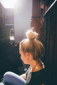 Close-up of young woman sitting outdoors in sunny day