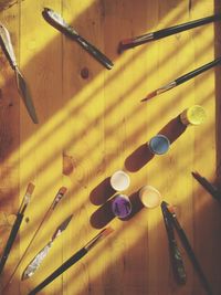 High angle view of paint and paintbrushes on wooden table