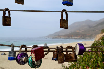 Close-up of padlocks hanging on railing against sky