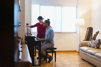 Man and woman using piano at home