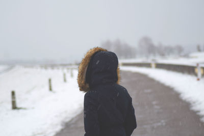 Woman standing on road during snowfall