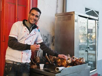Portrait of happy man standing on barbecue grill