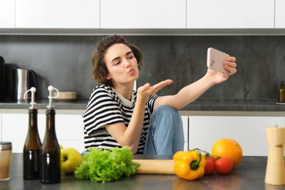 Portrait of smiling young woman holding food at home