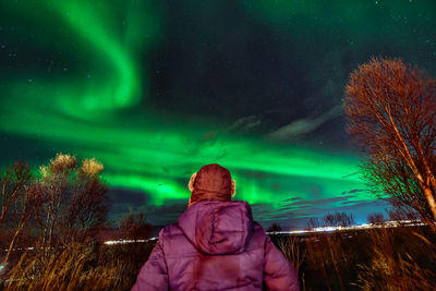 Rear view of mature man looking at aurora borealis in sky at night