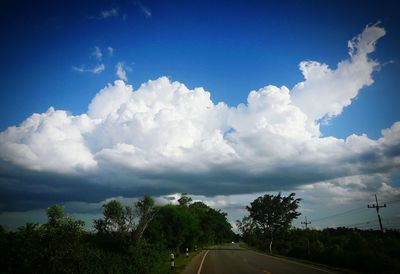 Road amidst trees against blue sky