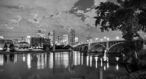 Bridge over river by buildings against sky in city