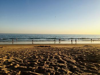 People at beach against clear sky