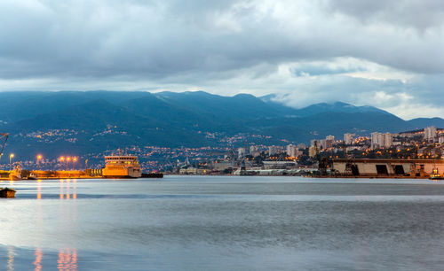 Buildings by sea against sky in city