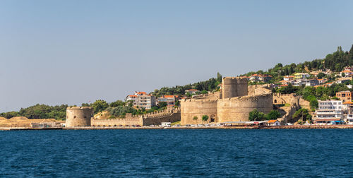 Buildings by sea against sky