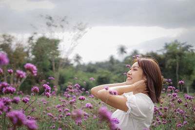 Side view of young woman looking at flowering plants