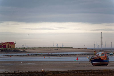 Sailboats on beach against sky in city