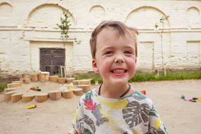 Portrait of smiling boy standing against building
