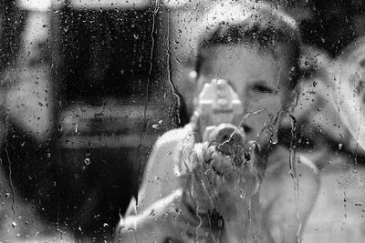 Portrait of woman seen through wet glass window