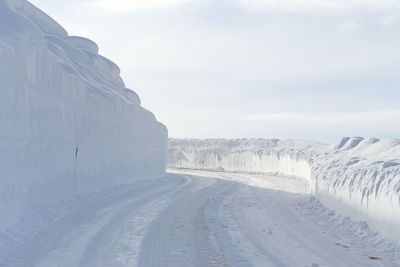 Snow covered road against sky.