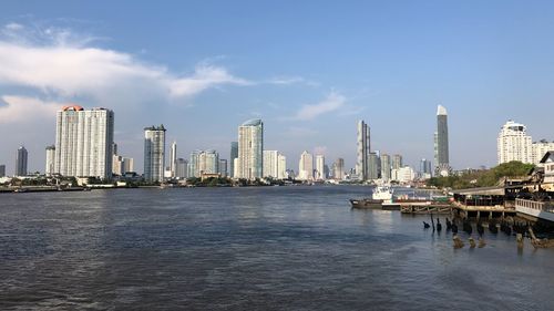 Sea and modern buildings in city against sky