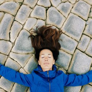 High angle portrait of woman lying on footpath