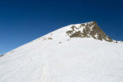 Low angle view of snowcapped mountain against clear blue sky