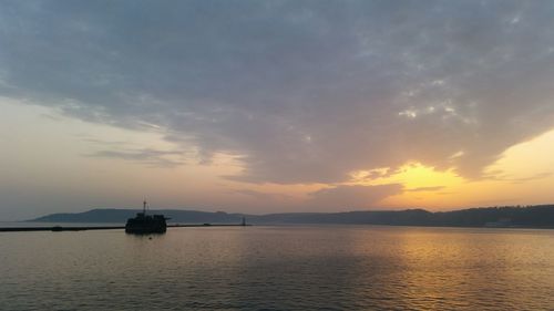 Scenic view of sea against cloudy sky at sunset