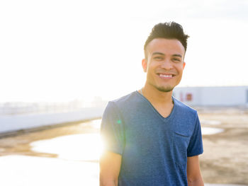 Portrait of smiling young man standing at beach