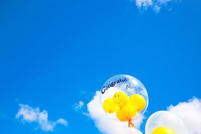 Low angle view of balloons with smiley faces against sky