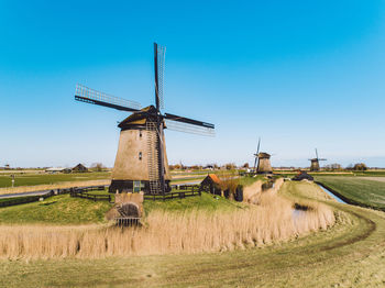 Traditional windmill on field against blue sky