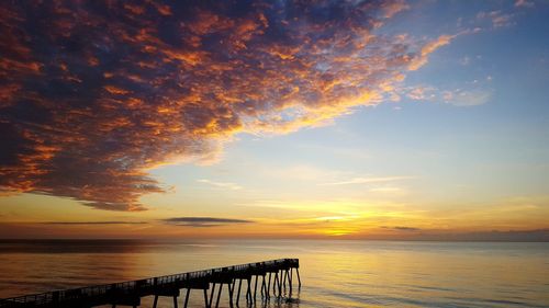 Scenic view of sea against dramatic sky during sunset