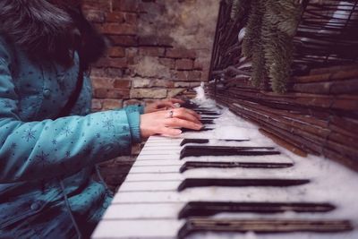 Midsection of woman playing abandoned piano during winter