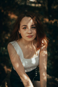 Portrait of young woman standing against trees