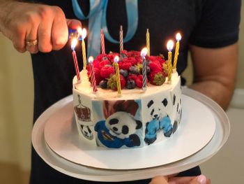 Midsection of man lighting candles on cake