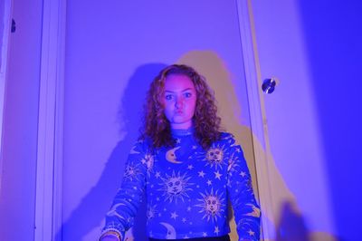 Portrait of woman standing against blue wall
