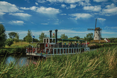 Old steamboat and windmill in canal with bushes near damme. a charming country village in belgium.