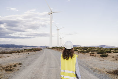 Engineer looking at wind turbines standing on dirt road