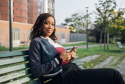 Smiling woman with mobile phone sitting on bench