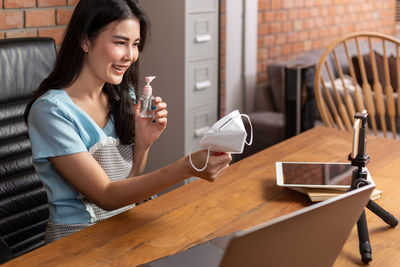 Young woman using smart phone while sitting on table