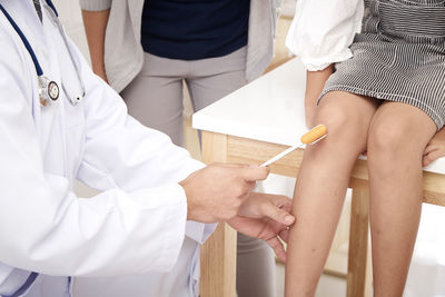 Cropped image of doctor examining knee of patient in clinic