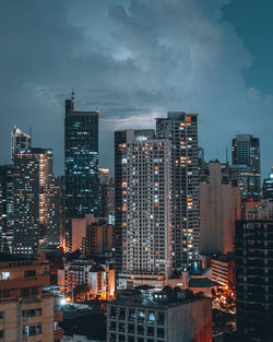 Illuminated buildings in city against sky at dusk