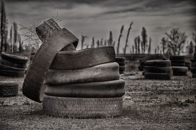 Obsolete tires on field against sky