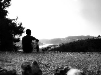 Rear view of man sitting on street against sky