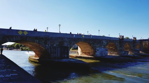 Arch bridge over river against clear blue sky