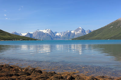 Scenic view of lake and mountains against blue sky