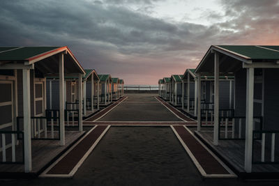 Empty road amidst buildings against sky during sunset