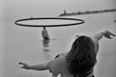 Woman with plastic hoop dancing at beach