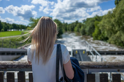 Rear view of woman standing on bridge over river