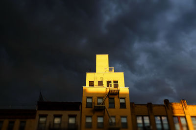 Low angle view of yellow building against cloudy sky