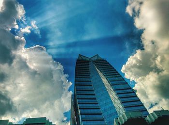 Low angle view of modern building against cloudy sky